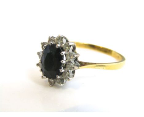 An 18k gold sapphire and diamond ladies cluster ring, central dark blue sapphire (8 x 6mm) with a surround of twelve single c