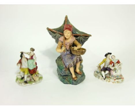 A 19th century continental figure of a seated fisher girl with a triangular shaped net on her back, seated on a rocky out cro