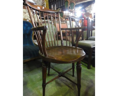 A Windsor style stained beechwood stick back elbow chair with shaped arms, circular saddle shaped seat raised on turned taper