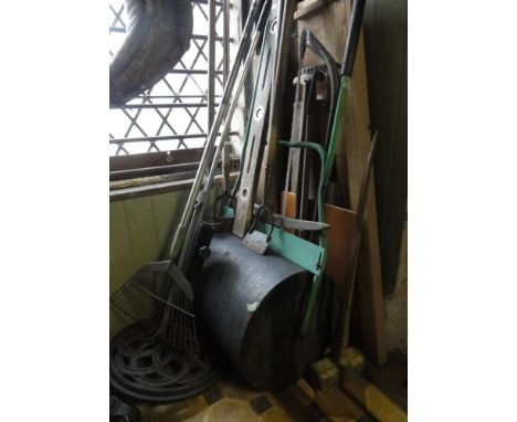 A collection of miscellaneous garden tools including a lawn roller, various hoes, rake, etc.