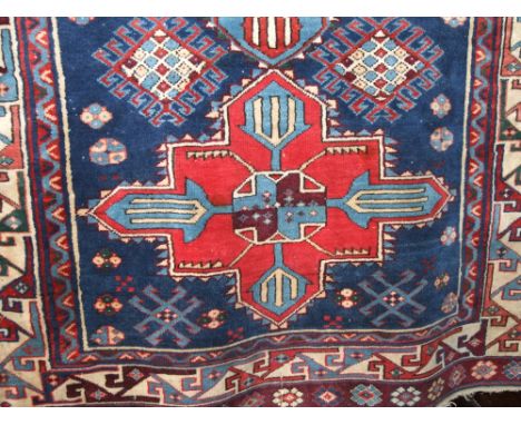 Afghan floor rug centrally decorated with red and blue medallions upon a navy blue and amethyst ground, 140 x 110cm