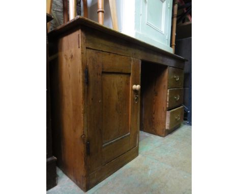 A vintage stripped pine kneehole desk, the rectangular top over three drawers and cupboard enclosed by a panelled door, 4ft 4