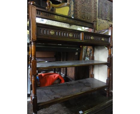 A small hardwood three tier buffet the raised back with pierced detail and mirrored plate over two frieze drawers and open sh