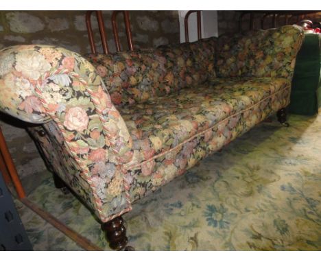 A late Victorian/Edwardian two to three seat double drop arm Chesterfield sofa with buttoned busy floral patterned upholstery