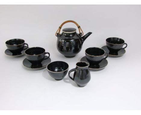 A set of studio pottery teawares by Lucie Rie, all with dark brown glaze and of simple form, comprising a kettle with cane ha