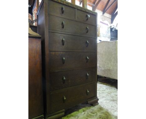 An early 20th century oak upright bedroom chest of five long and two short drawers beneath a moulded frieze raised on ogee br