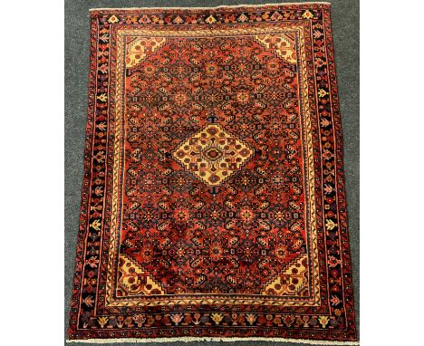 A North-West Persian Malayer or Malayir rug / carpet, knotted in tones of deep red, blue, black, and cream, the central diamo