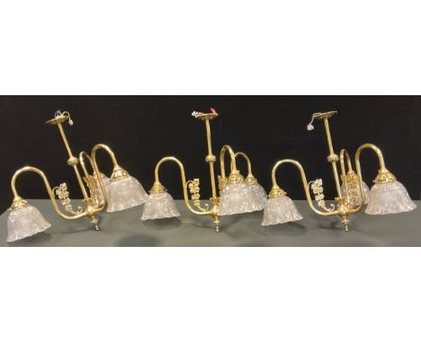 A set of three brass three light pendant light fittings, each with tubular and globular bodies, three floral accented arms, m