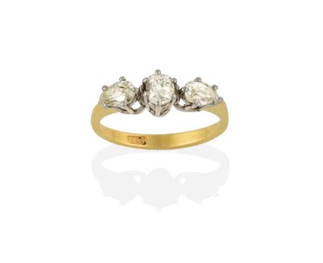 A Diamond Three Stone Ring, an old cut diamond flanked by pear shaped diamonds, in white claw settings, to a yellow tapered s