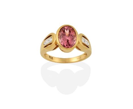An 18 Carat Gold Garnet and Diamond Ring, the oval cut garnet in a yellow rubbed over setting, to a round brilliant cut diamo