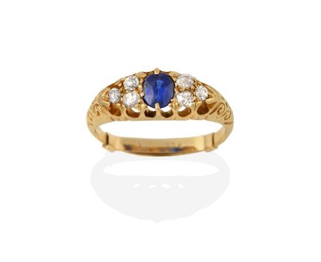 A Sapphire and Diamond Ring, the oval cut sapphire flanked by trios of old cut diamonds in yellow claw settings, to a fancy s