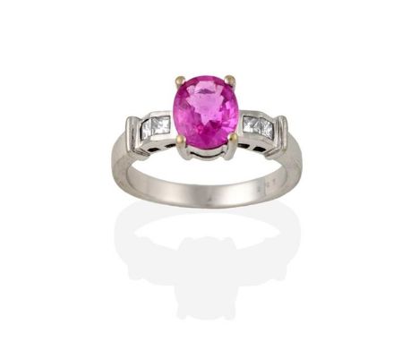 A Pink Sapphire and Diamond Ring, the oval cut pink sapphire in a white claw setting, to a princess cut diamond set shoulder 