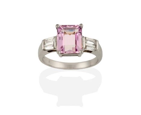 A Kunzite and Diamond Ring, the emerald-cut kunzite flanked by pairs of tapered baguette cut diamonds in white claw settings,