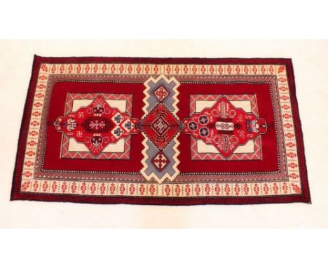 A tapestry rug with geometrical design on a red background - 170cm by 87cm