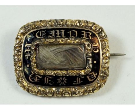 A late Georgian/early Victorian yellow metal mourning brooch with black enamel background and gilt script 'In Memory Of' with