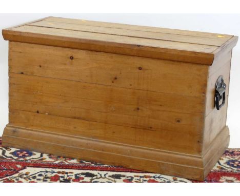 A stained and boarded pine hinge top tool chest, having iron end carry handles, width 82cm