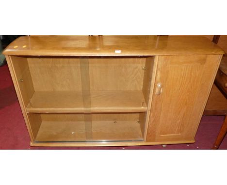 An elm low bookshelf, having twin glazed sliding doors and single panelled cupboard door, in the Ercol style, width 136cm