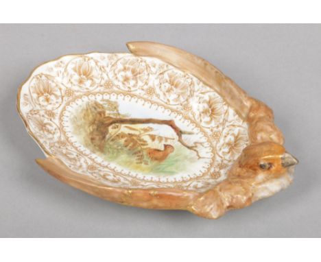 A Royal Worcester pin dish moulded to the rim with a bird. Printed with a border of stylized flowers and painted to the centr