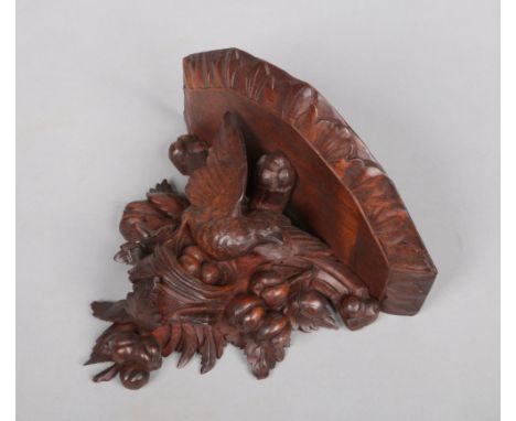 A Black Forest carved walnut wall bracket surmounted with a nesting bird, 24cm wide, 19cm high.