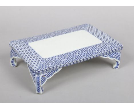 A Japanese porcelain rectangular blue and white stand. Painted in underglaze blue with fretwork panels and raised on bracket 