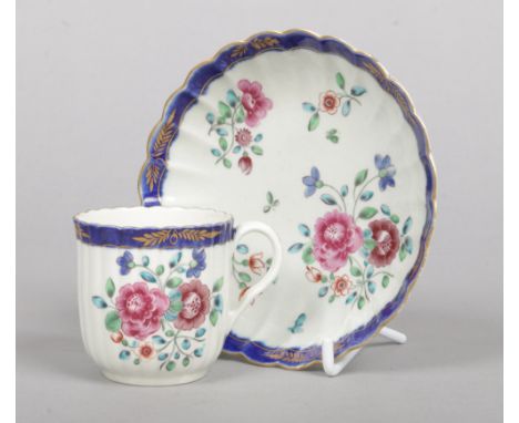 A Worcester fluted coffee cup and saucer. Decorated in coloured enamels with flowers under a blue and gilt border. Underglaze