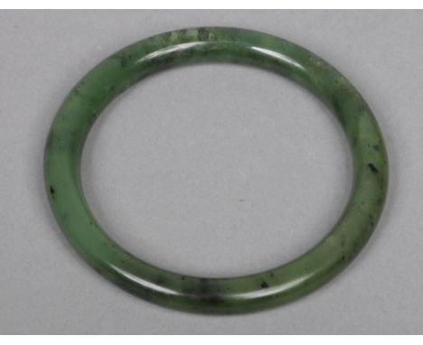 A Chinese mottled spinach jade bangle, 76mm outer diameter.