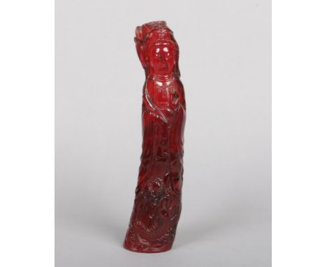 A Chinese carved cherry amber coloured statue of Guanyin. Dressed in flowing robes and holding a lily stem. 636 grams, 27cm.