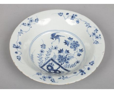 An 18th century English blue and white delft soup plate, probably Vauxhall. Painted with flowers and a bird in flight, 22.25c