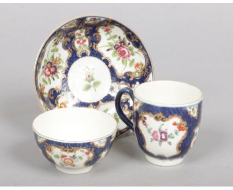 A Worcester trio comprising a teabowl, coffee cup and saucer. Scale blue ground and with gilt cartouches containing English f