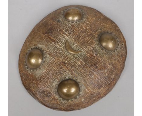 A 19th century Indo-Persian small tortoiseshell roundel shield with brass adornments, 30cm.