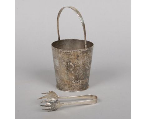 A Chinese silver ice bucket with swing handle, drainer and tongues. Planished and engraved with a dragon chasing a flaming pe