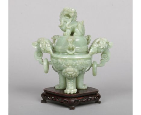 A 20th century Chinese hardstone jade coloured censor and cover on hardwood stand. Carved with a temple dog finial, with twin