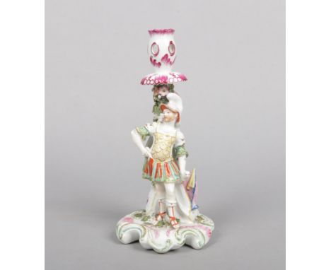 A Derby figural candlestick modelled as a centurion representing Mars with a shield and flag by his side. Raised on a rococo 