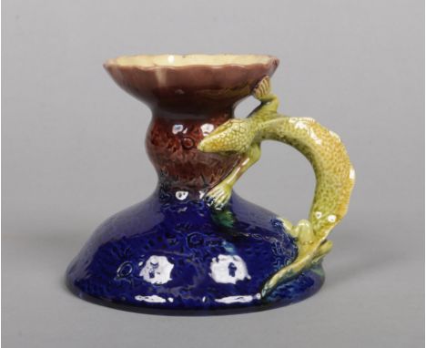 A Burmantofts Faience chamber stick. The handle formed as a surmounted lizard, glazed in blue, brown and green. Impressed mar