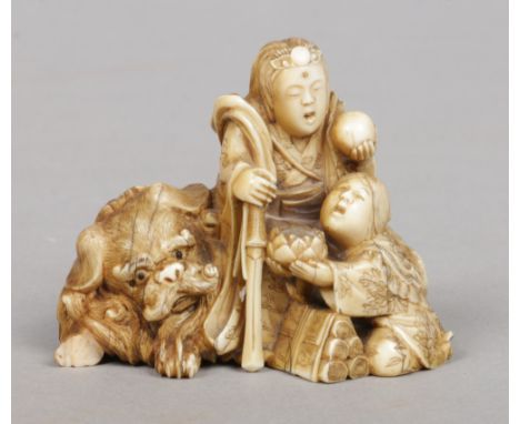 A Japanese Meiji period carved ivory netsuke. Modelled as a pair of figures and a recumbent lion dog. Signed to the underside