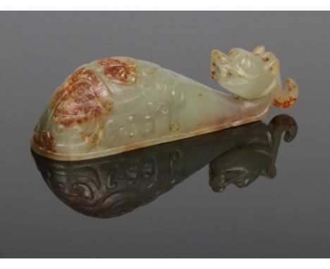 A Chinese archaistic carved celadon jade belt buckle with russet suffusions. The pommel carved in the form of a pixiu head, 9