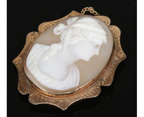 A 9 carat gold mounted carved shell cameo brooch. Depicting the profile portrait of a Grecian woman, 4cm x 5cm.