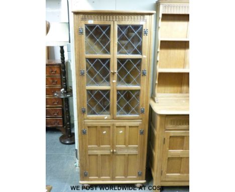 A light oak glazed corner cupboard in the Arts and Crafts style (H169 x W68 x D35cm)