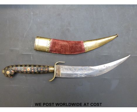 An Indian jambiya dagger with engraved 18cm curved blade, brass inlaid horn handle and coral beads, in brass and velvet scabb