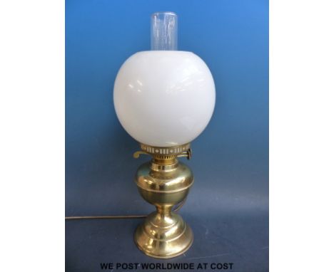A brass oil lamp converted for modern electric use complete with glass shade