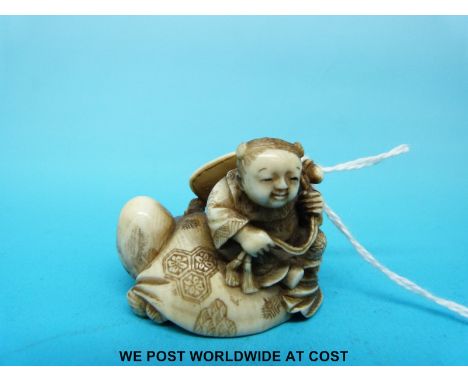 A signed Japanese Meiji period carved ivory netsuke of a crawling man with a child on his back (3.5cm tall)