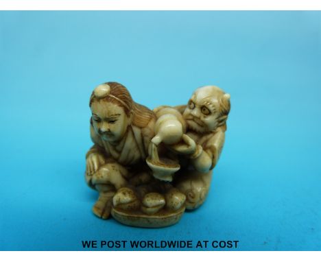 A Japanese Meiji period signed carved ivory netsuke of a horned figure pouring liquid into a woman's bowl (3.3cm tall)