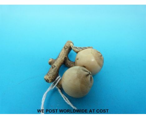 A signed Japanese Meiji period carved ivory netsuke in the form of two pomegranates and a leaf hanging from a branch (5cm lon