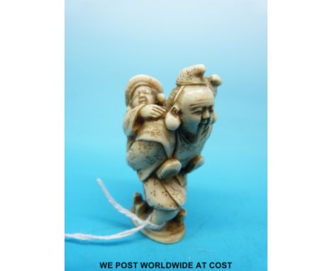 A Japanese Meiji period carved ivory netsuke of a bearded man carrying a child (5.2cm tall)