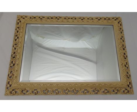 A rectangular carved and pierced painted wooden frame wall mirror, 63.5 x 89cm