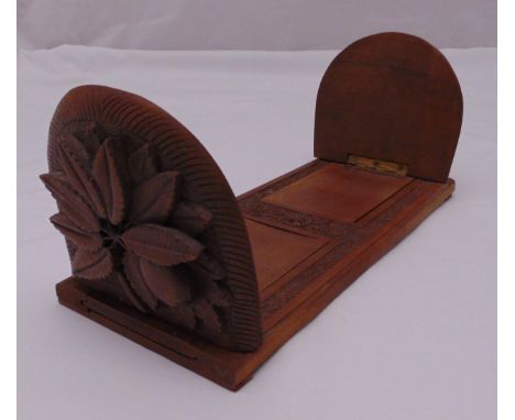 A rectangular carved wooden book slide, the hinged ends carved with stylised leaves, 33cm (w)