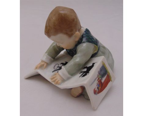 A Meissen Art Nouveau figurine of a child reading a picture book by Julius Conrad Hentschel, marks to the base, 10 x 12 x 11c