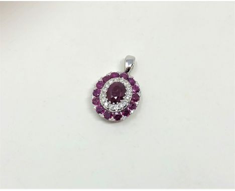 A 14ct white gold ruby and diamond pendant, featuring centre oval cut ruby (1.29ct), claw set with fourteen round cut rubies 