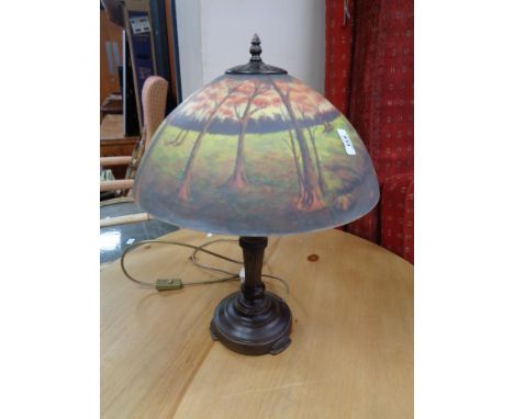 A reproduction table lamp with glass shade depicting a forest landscape