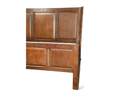 An Arts &amp; Crafts panelled double bed, the three panelled headboard carved 'WE ARE SUCH STUFF AS DREAMS ARE MADE ON', the 